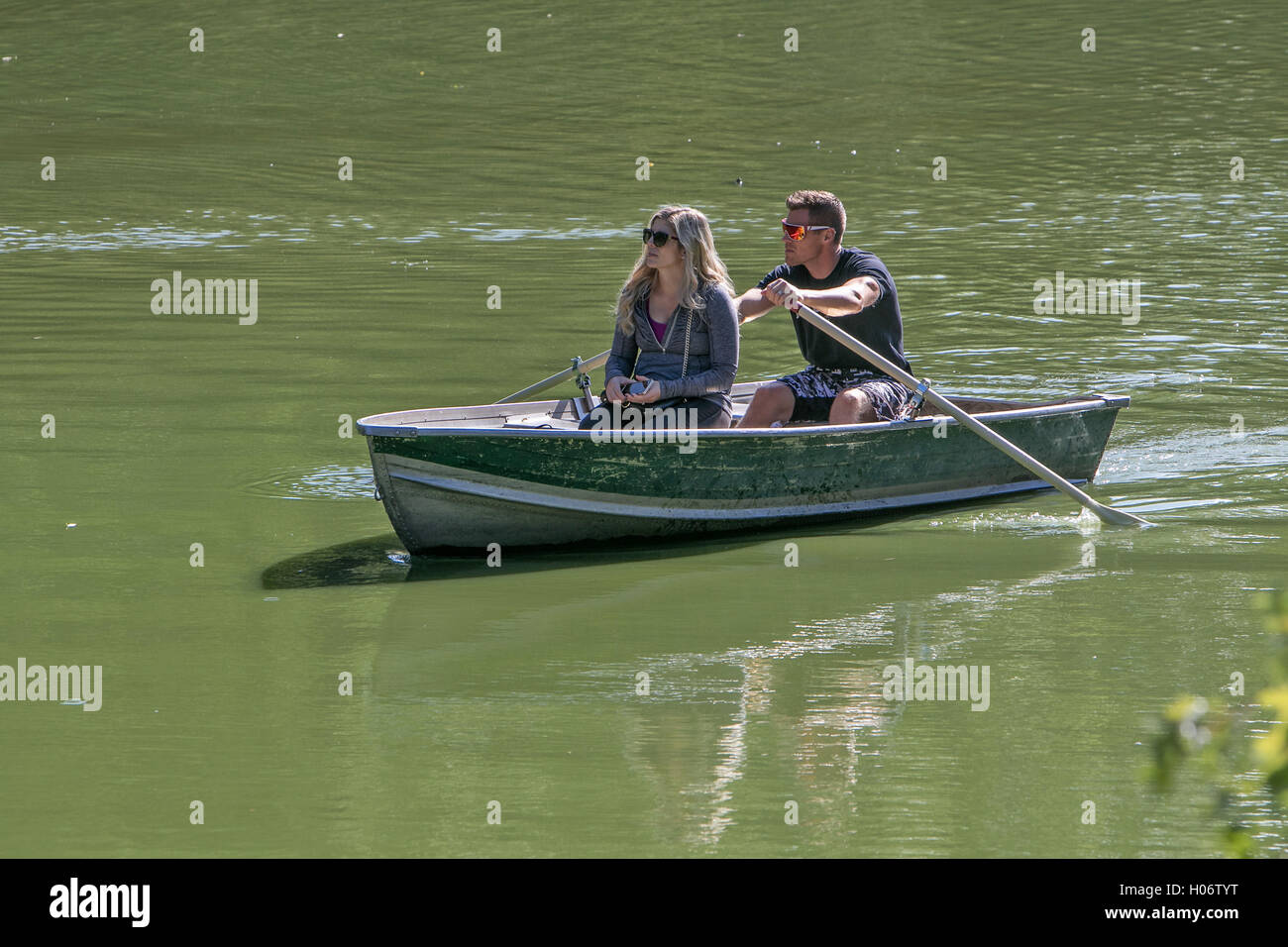 Un giovane sta godendo di fila gite in barca nel parco centrale. Foto Stock