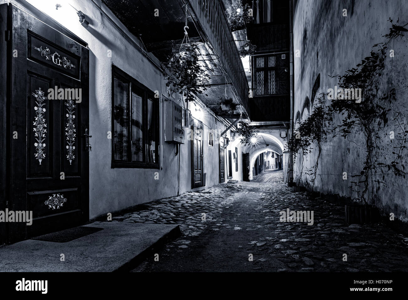 Moody visualizzazione monocromatica di una strada di ciottoli passaggio nel centro della città vecchia di Sibiu, Romania Foto Stock