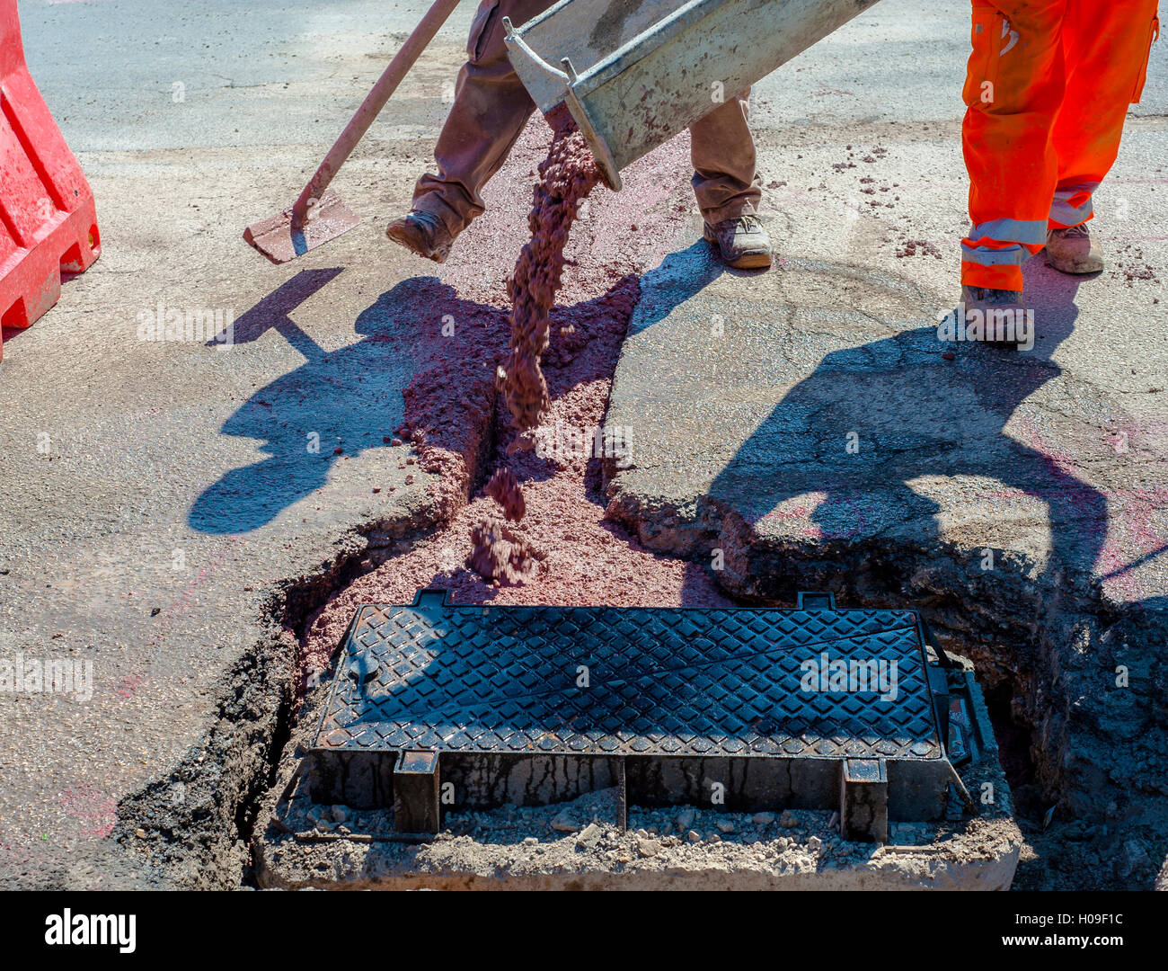 Cavi a fibra ottica sepolto in un micro trench con calcestruzzo colorato di rosso da un lavoratore Foto Stock