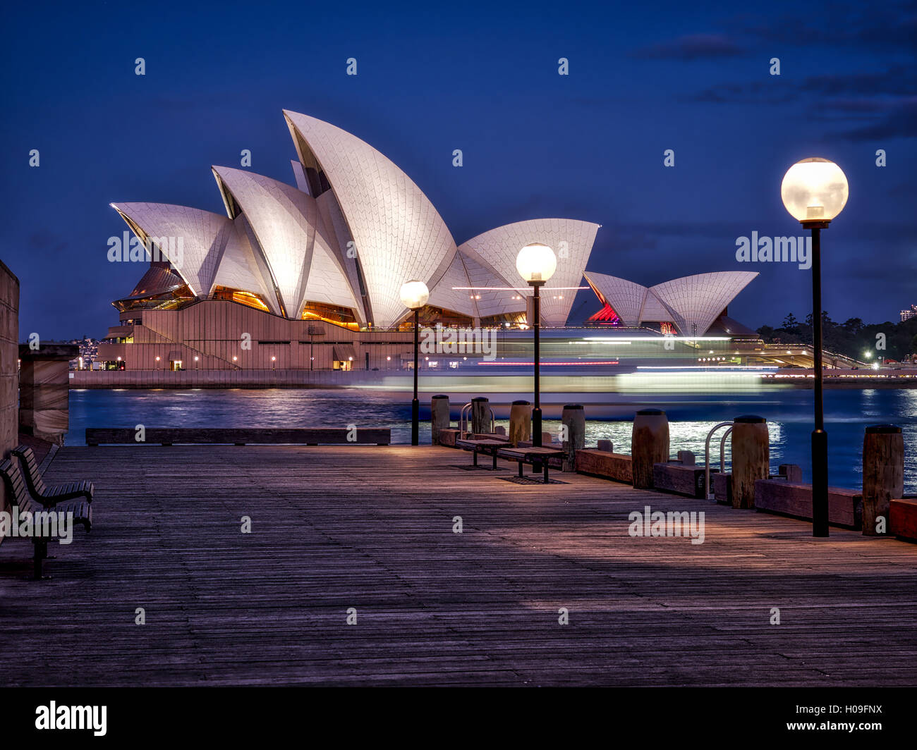 Una barca passa per la Sydney Opera House, Sito Patrimonio Mondiale dell'UNESCO, durante le ore di colore blu, Sydney, Nuovo Galles del Sud, Australia Foto Stock