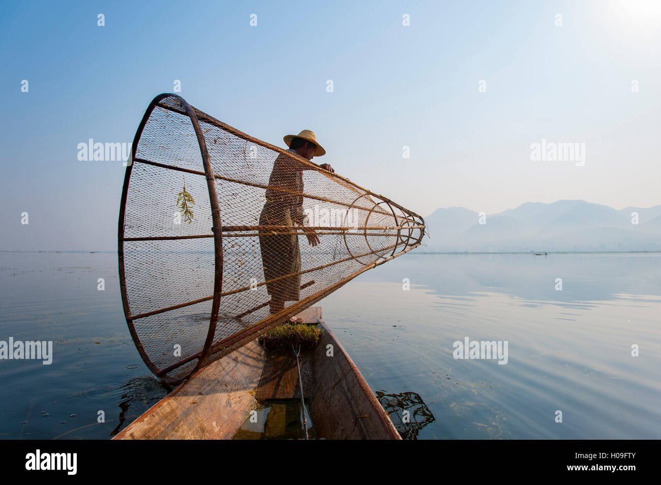 Un cestello pescatore sul Lago Inle si prepara a immergere il suo conformata a cono net, Stato Shan, Myanmar (Birmania), Asia Foto Stock