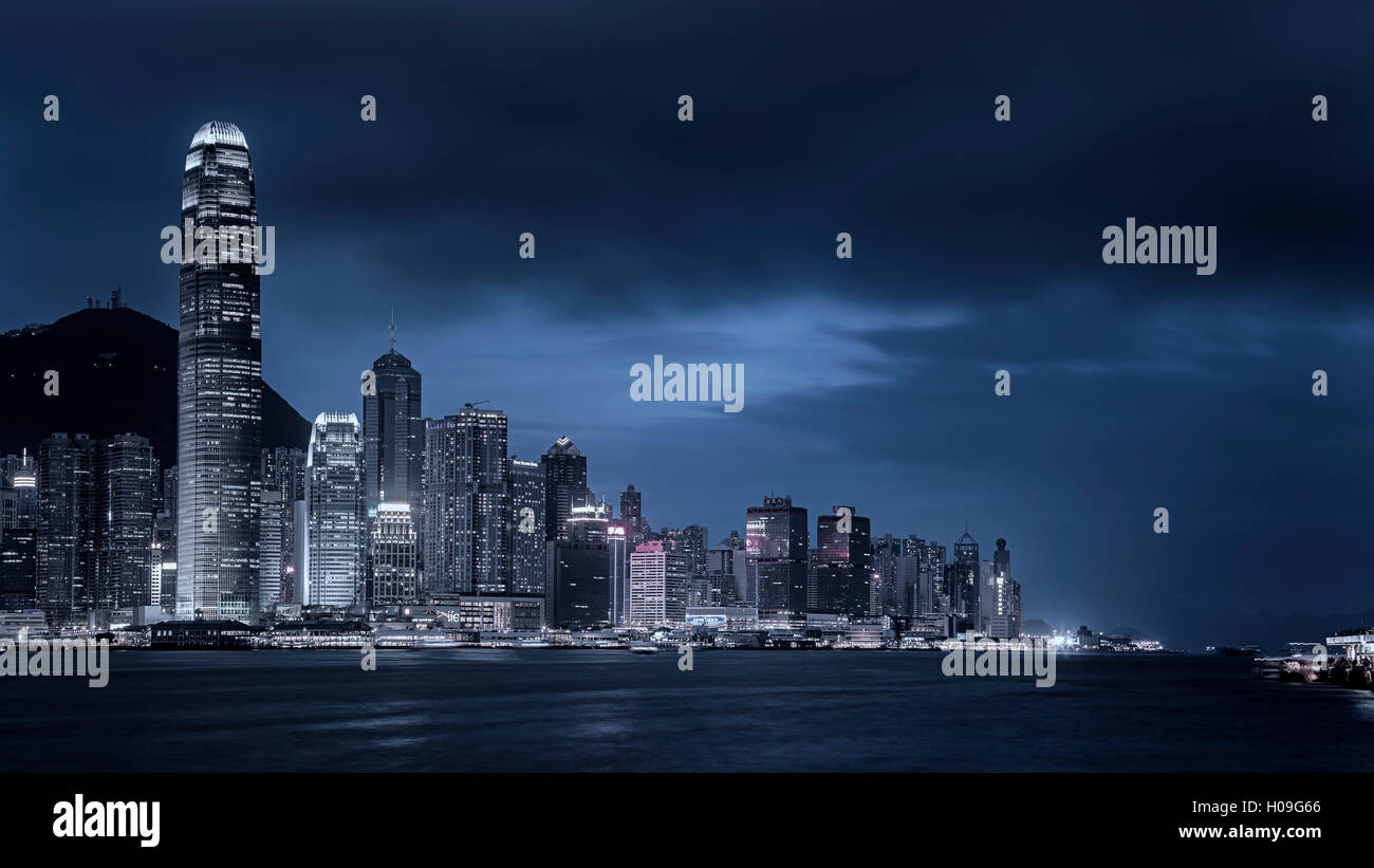 Guardando attraverso il Victoria Harbour per i grattacieli sull isola di Hong Kong con il Victoria Peak al di là di notte, Hong Kong, Cina Foto Stock