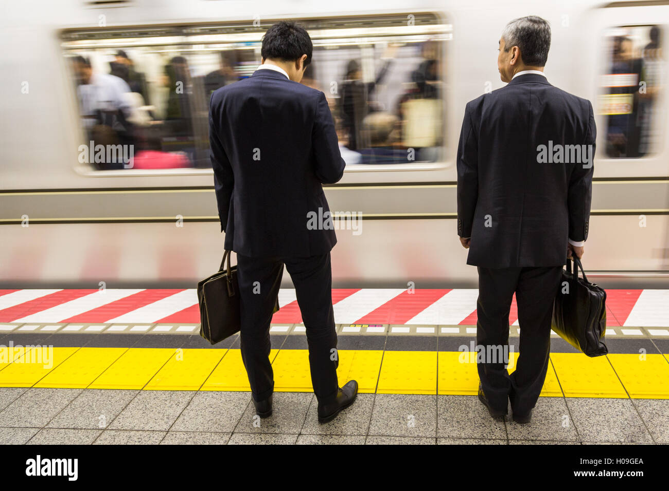 Due imprenditori in attesa di un treno della metropolitana di Tokyo, Tokyo, Giappone, Asia Foto Stock
