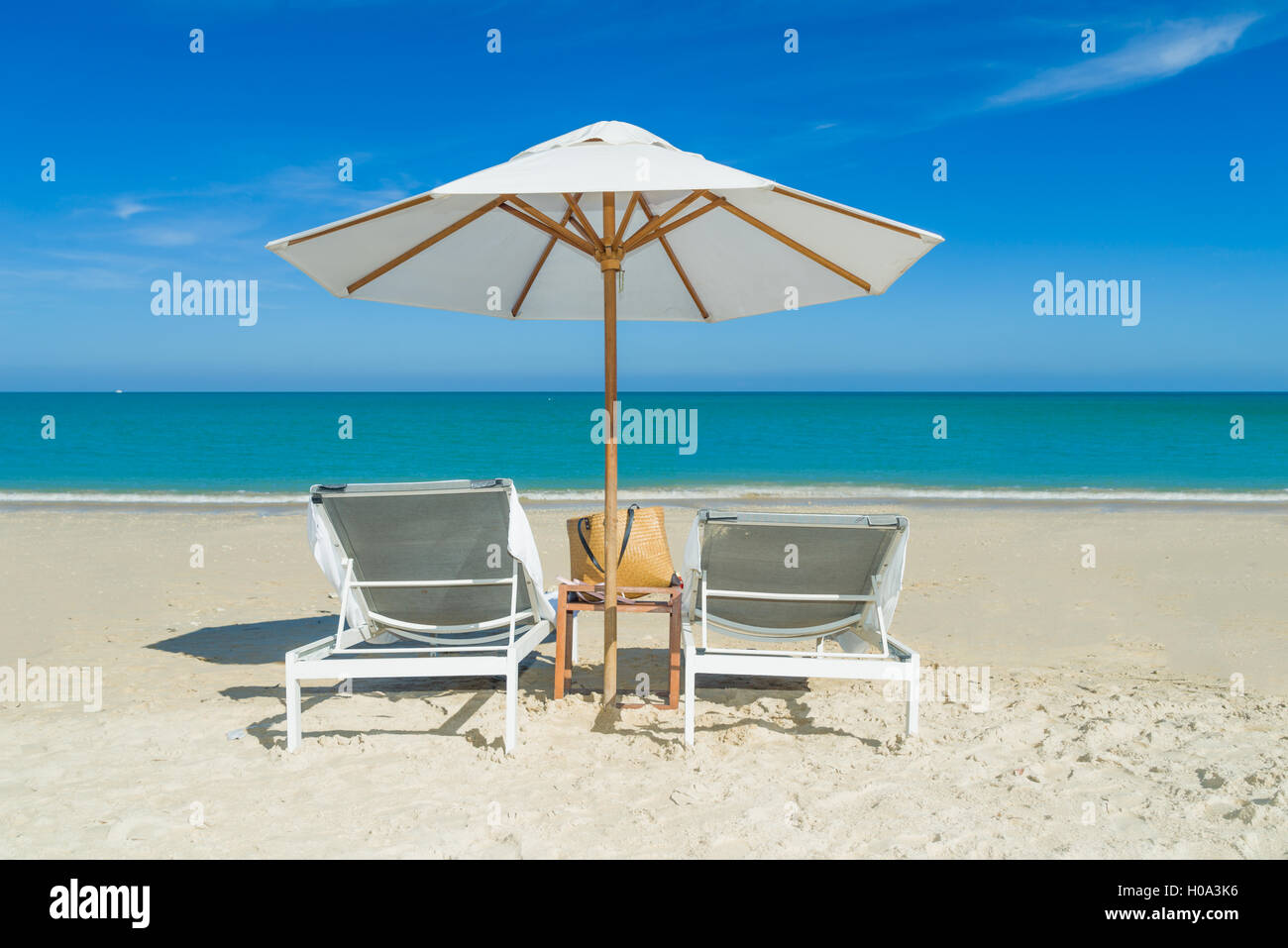 Sedie a sdraio sulla spiaggia di sabbia bianca con nuvoloso cielo blu Foto Stock