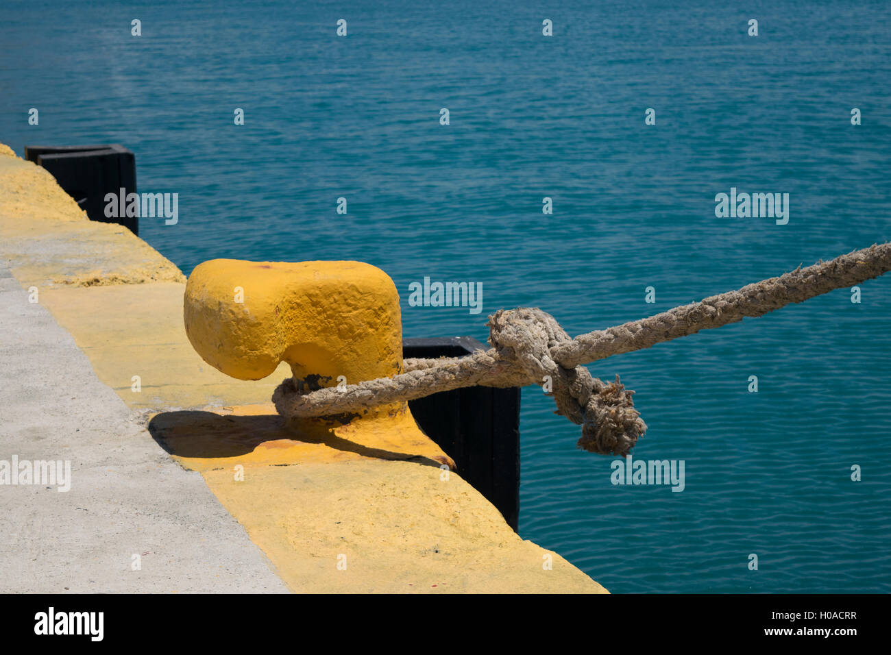 Rimorchiatore ancorata in un porto di Corinto in Grecia. Corda allacciate attorno al dispositivo di ancoraggio nel lato del molo Foto Stock