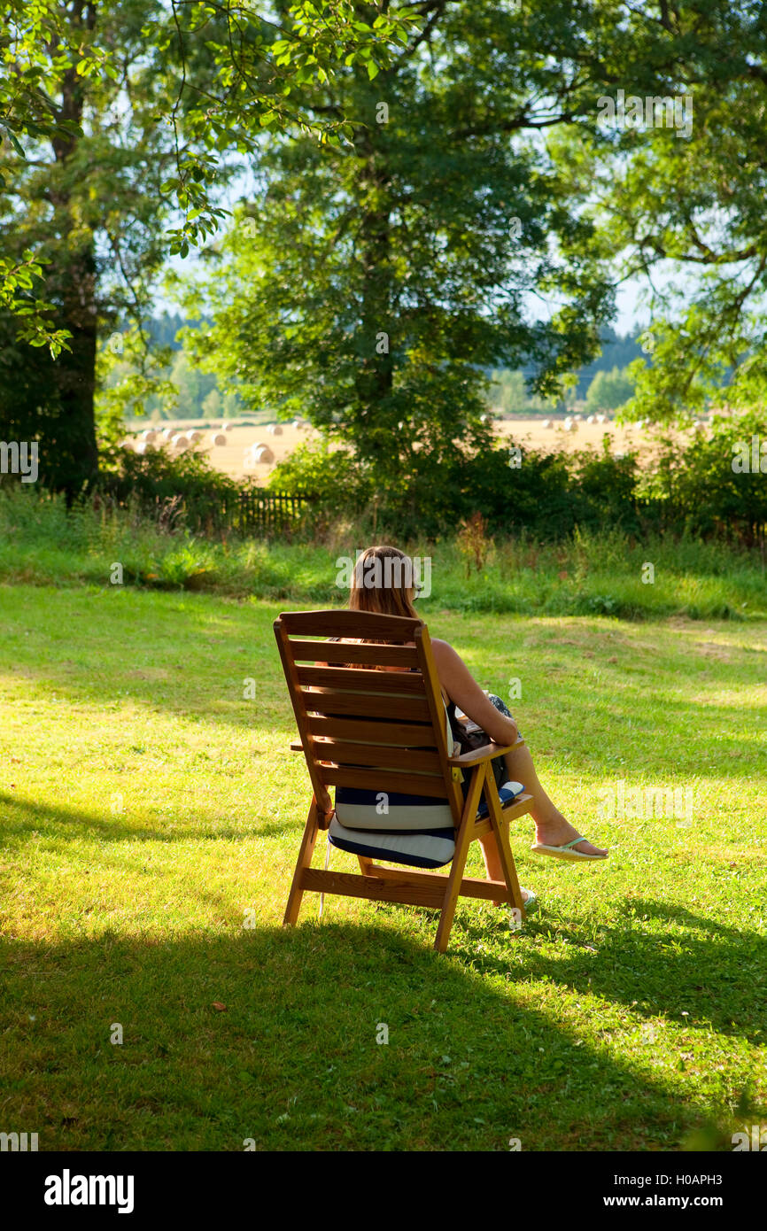 La donna la lettura di un libro in giardino Foto Stock