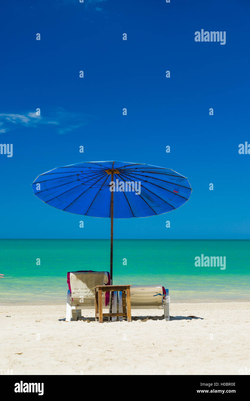 Sedie a sdraio sulla spiaggia di sabbia bianca con nuvoloso cielo blu Foto Stock