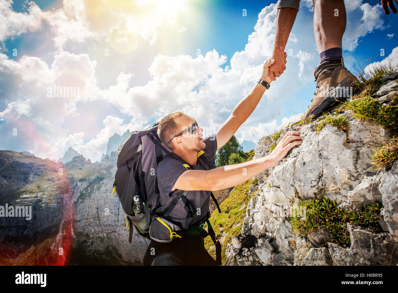 Gentile mano sull'Alta Montagna escursione. Gli uomini aiutando altri escursionisti dandogli la mano. Escursionismo Tema. Foto Stock