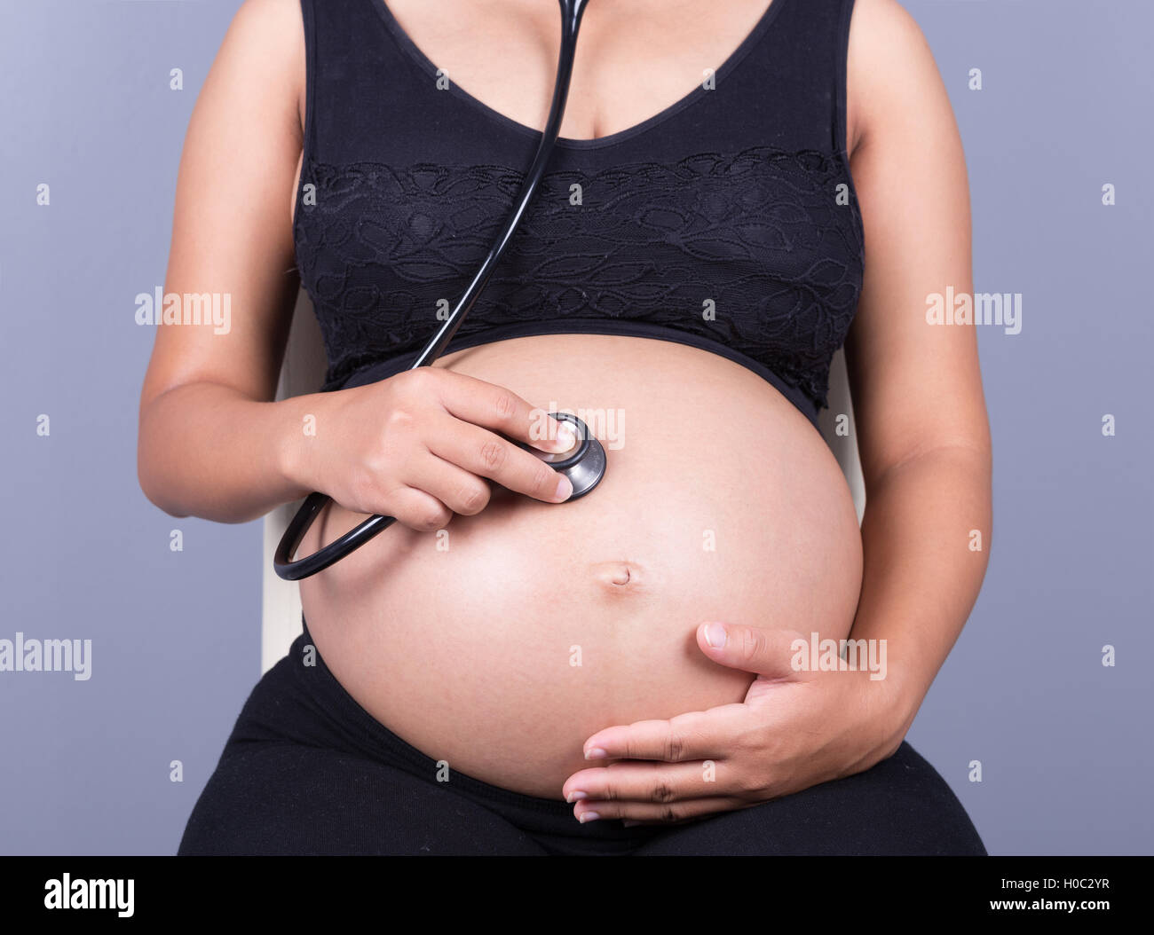 Close-up di una donna in stato di gravidanza con stetoscopio ventre di ascolto per baby Foto Stock