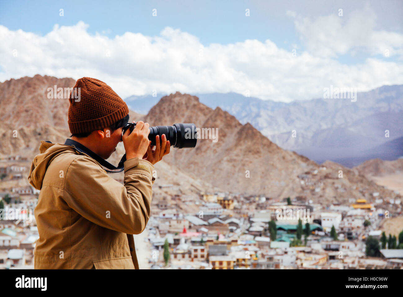 Close-up di viaggio giornalista fotografo tenendo una fotocamera reflex digitale in background di montagna Foto Stock