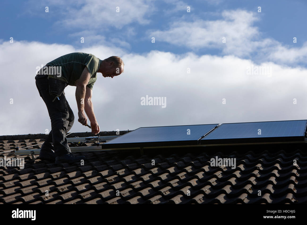 Uomo di installare sul tetto pannello solare array in un interno pannello solare installazione nel Regno Unito Foto Stock
