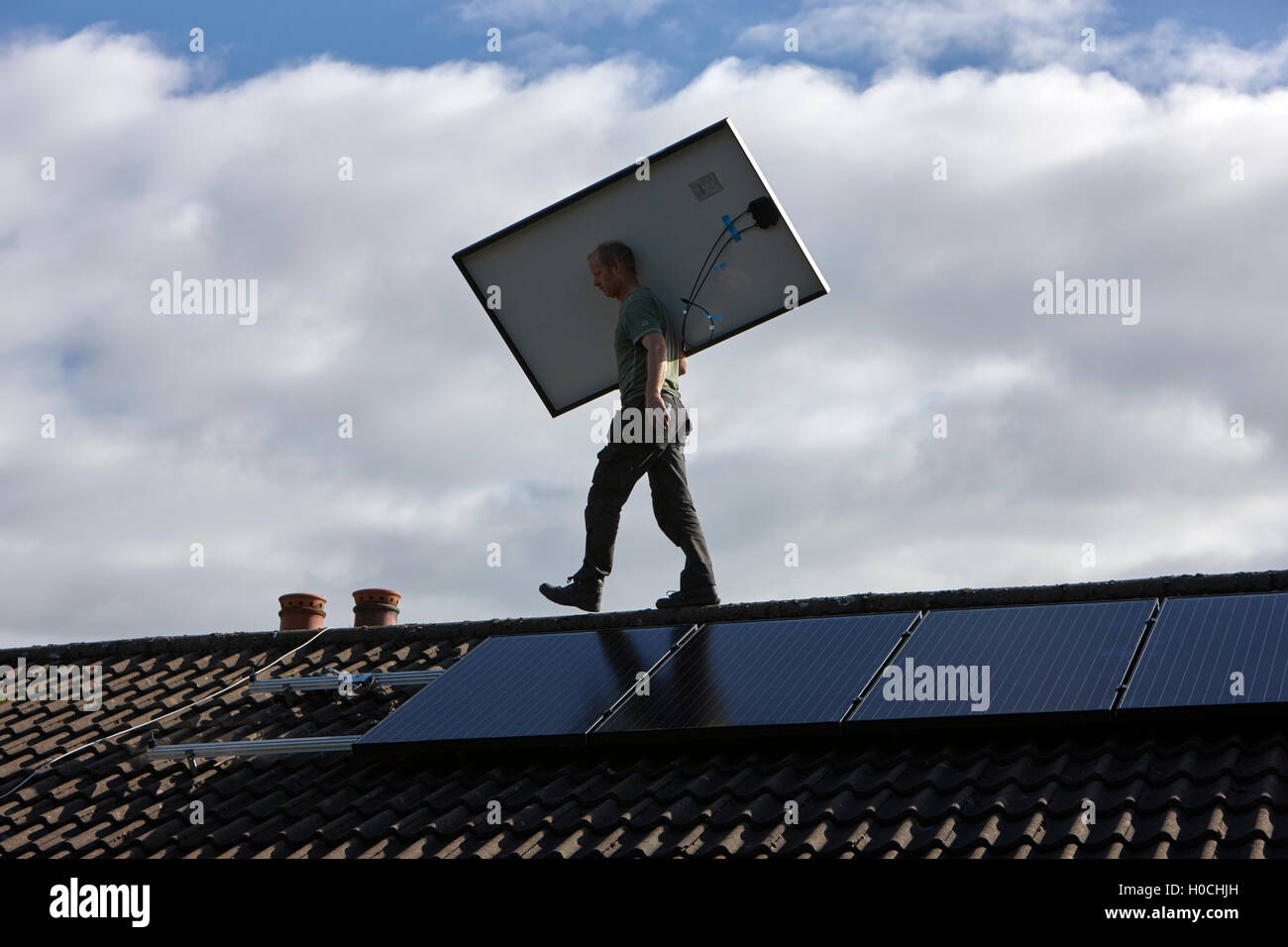 Uomo di installare sul tetto pannello solare array in un interno pannello solare installazione nel Regno Unito Foto Stock