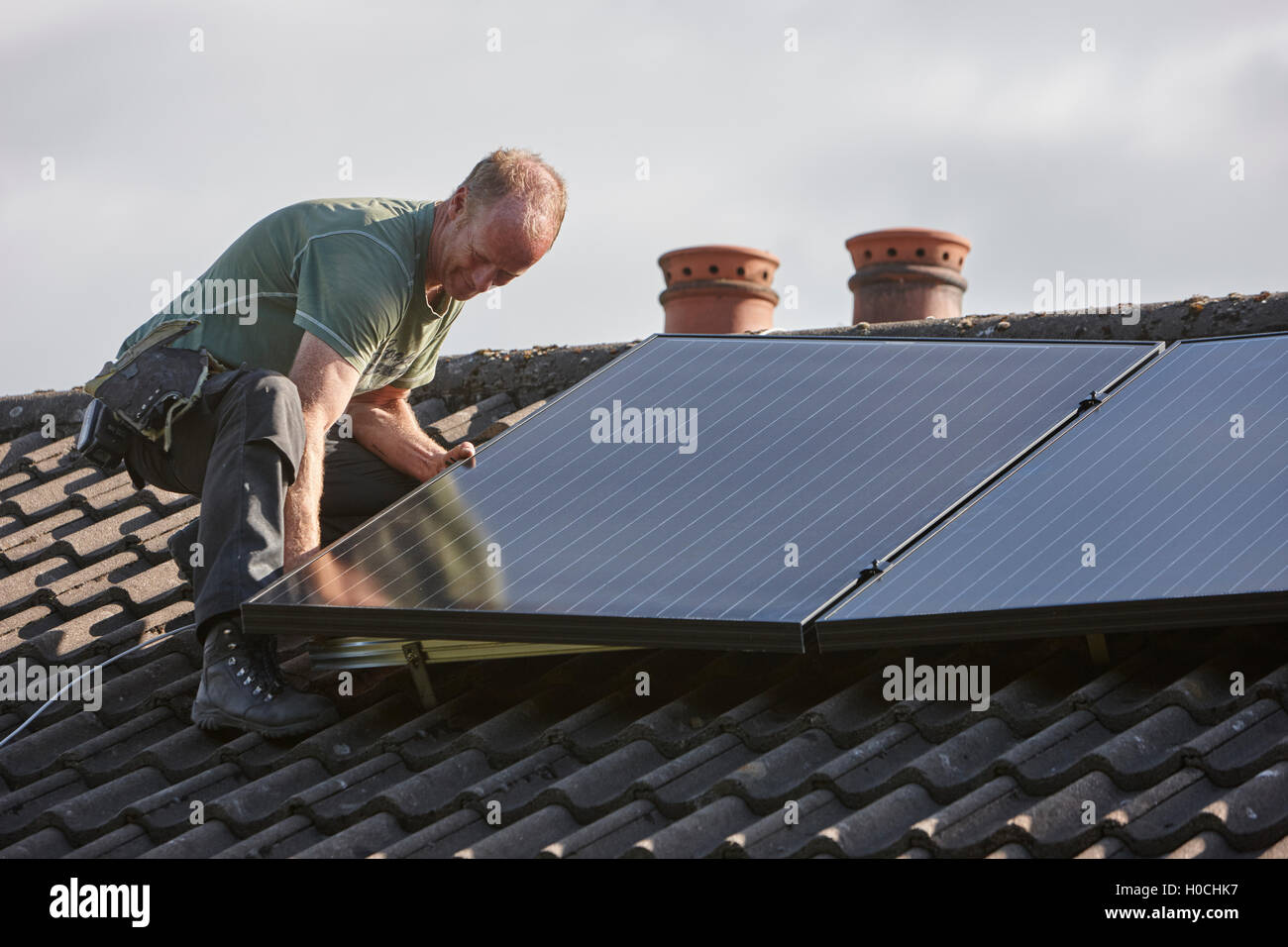 Uomo di installare sul tetto pannello solare array in un interno pannello solare installazione nel Regno Unito Foto Stock