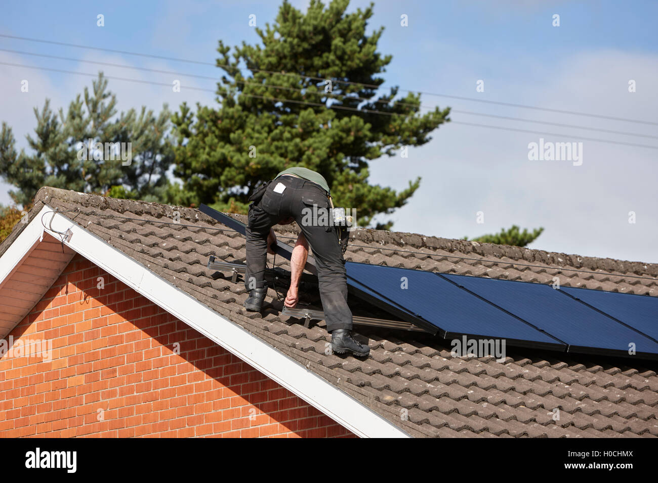 Uomo di installare sul tetto pannello solare array in un interno pannello solare installazione nel Regno Unito Foto Stock