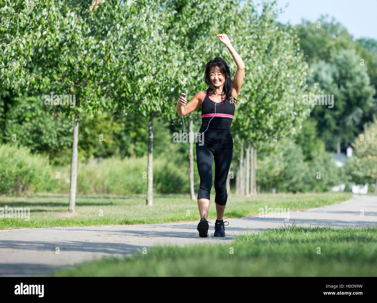 Americano asiatico a piedi femmina e ascolto di musica Foto Stock