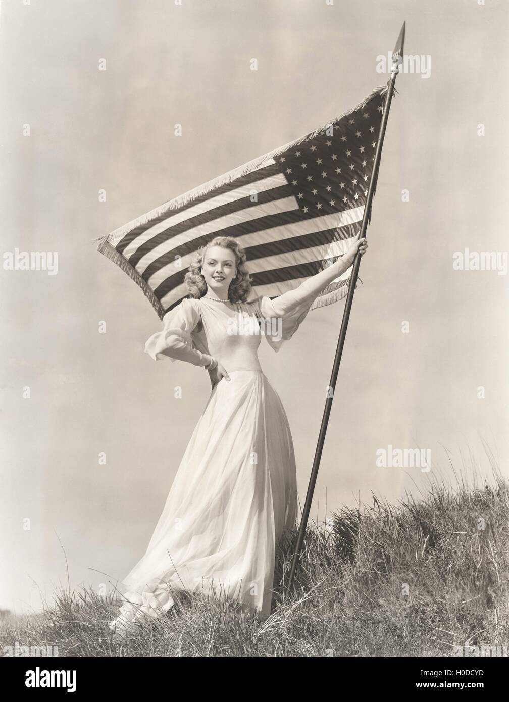 Orgogliosa donna in vestaglia holding bandiera americana sulla collina Foto Stock