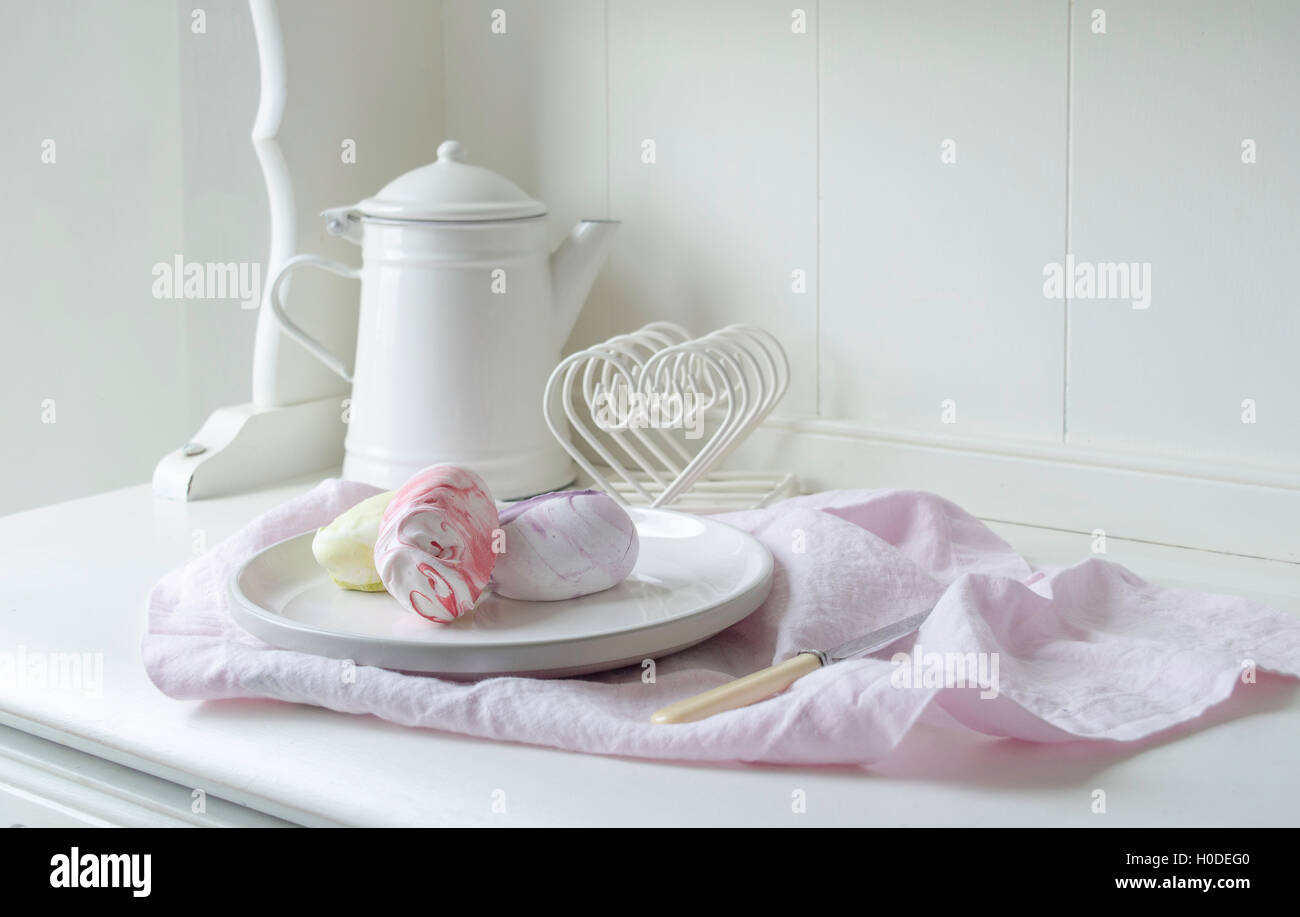 Stile pastello meringa Stock Photo su una cucina bianca in stile buffet con smalto bianco POT del caffè. Rosa pastello tovagliolo di lino nel tiro. Foto Stock