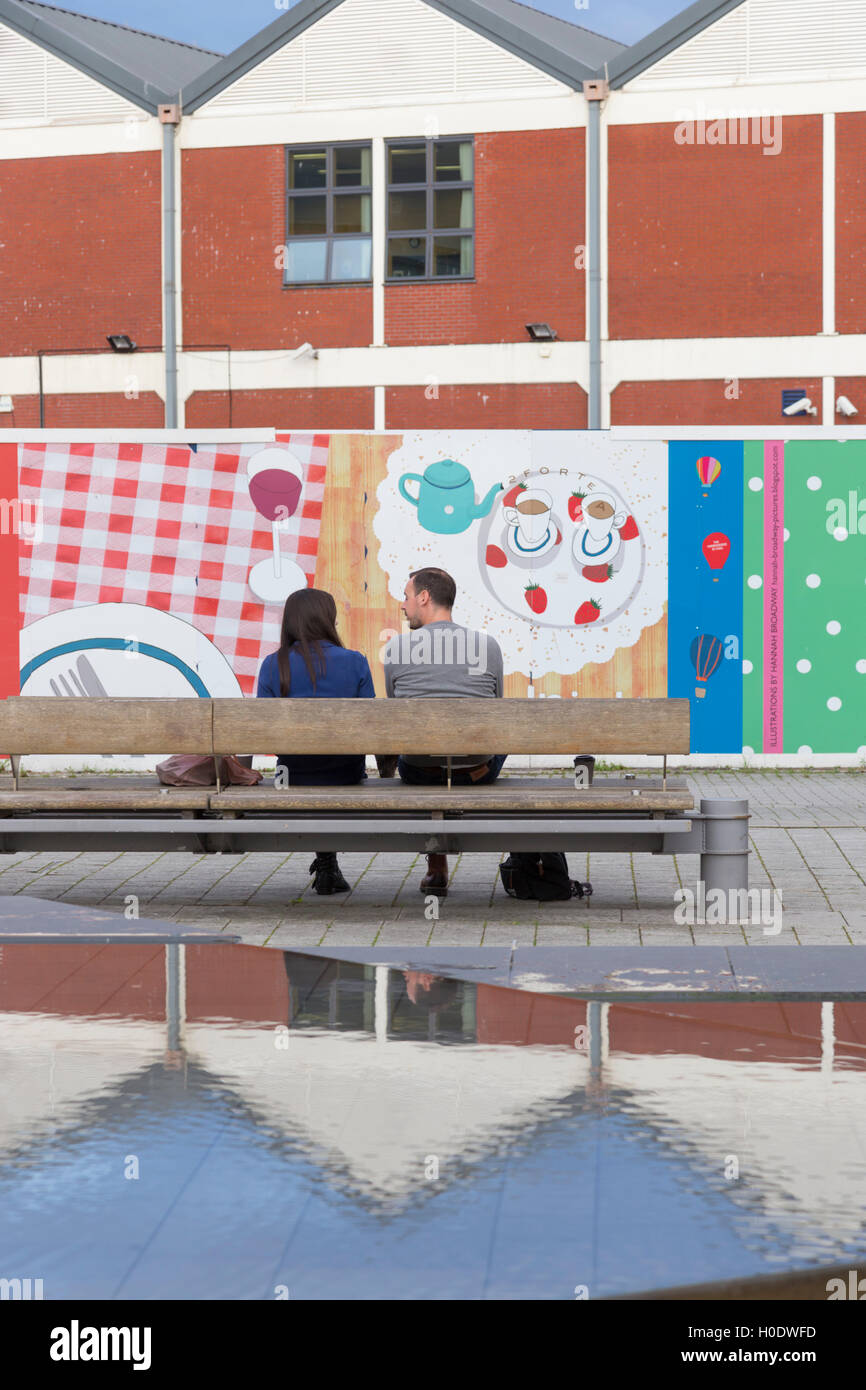 Un paio di parlare in un colorato Millennium Square, Bristol, Inghilterra, Regno Unito Foto Stock