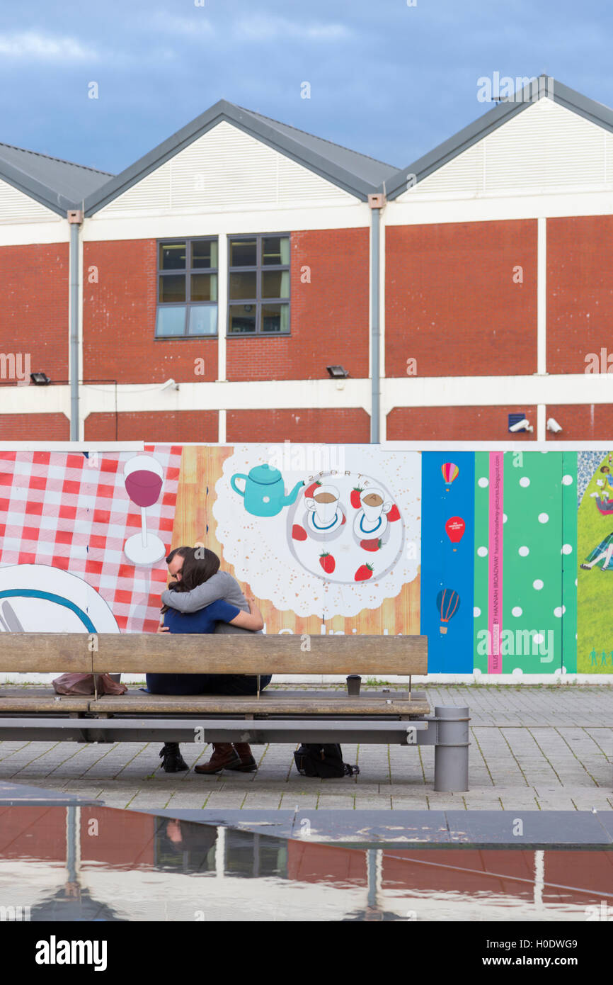 Un paio di abbracciare in un colorato Millennium Square, Bristol, Inghilterra, Regno Unito Foto Stock
