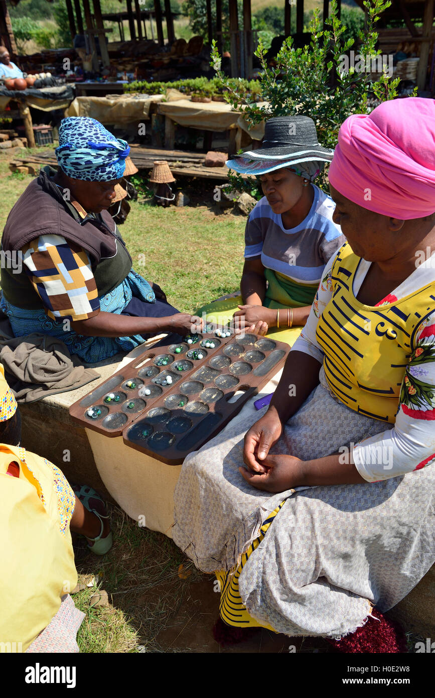 Tre donne del mercato si bancarelle a Mac Mac Falls che si sciolcono tempo giocando Mancala - l'African Stone Game, Sud Africa Foto Stock
