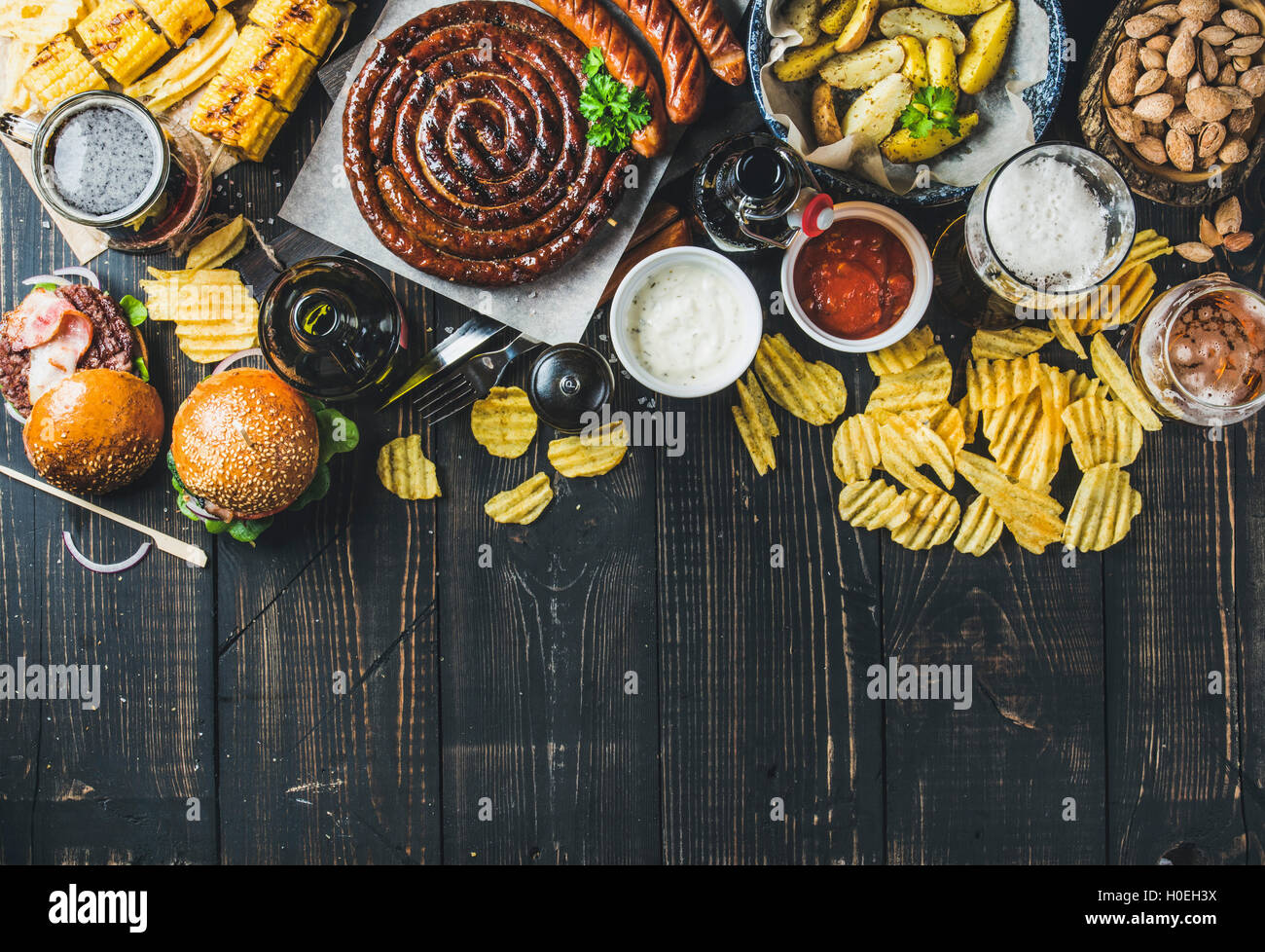 Birra e snack set. Oktoberfest cibo concetto di frame. Vatiety di birre, salsicce alla griglia, hamburger, mais, patate fritte, patatine, sa Foto Stock