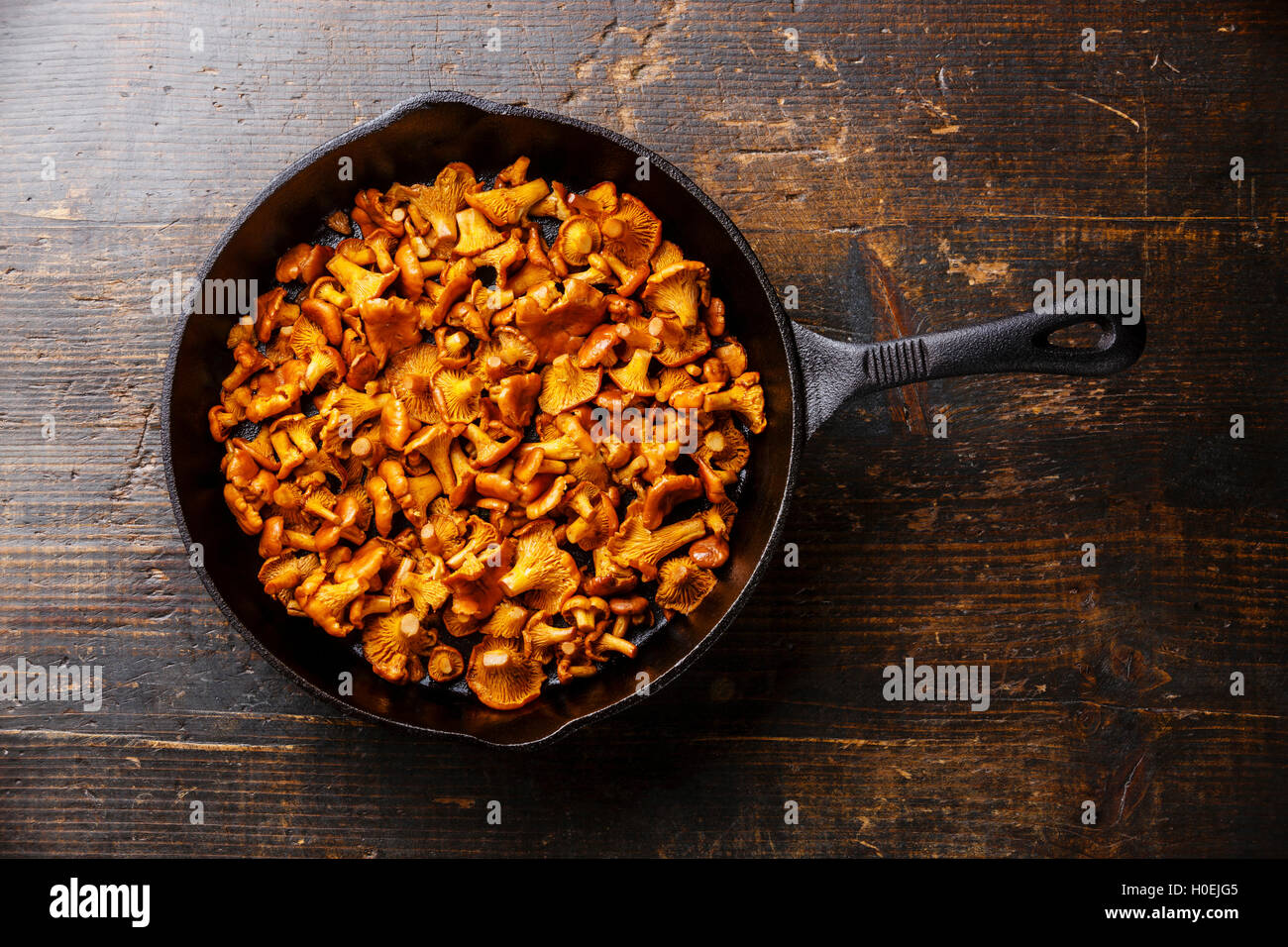 Arrosto di bosco selvatico funghi chanterelle in tegame su sfondo di legno Foto Stock