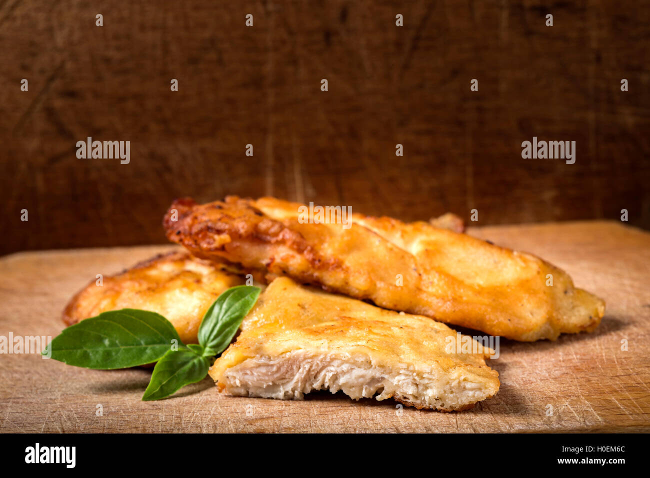 Pollo fritto cotoletta su legno con basilico Foto Stock