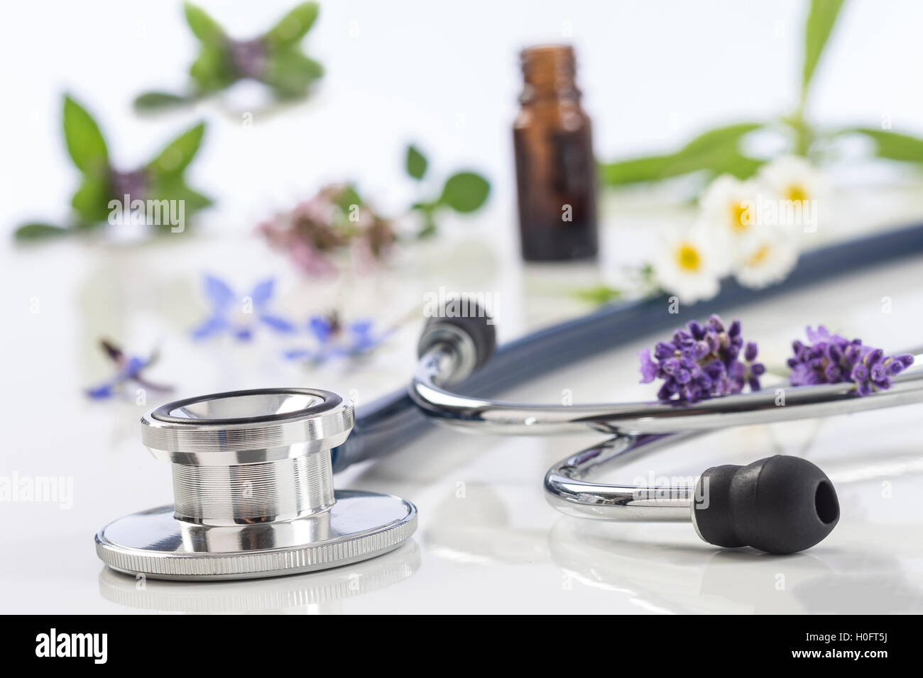 Bottiglia di olio essenziale di piante medicinali e uno stetoscopio Foto Stock