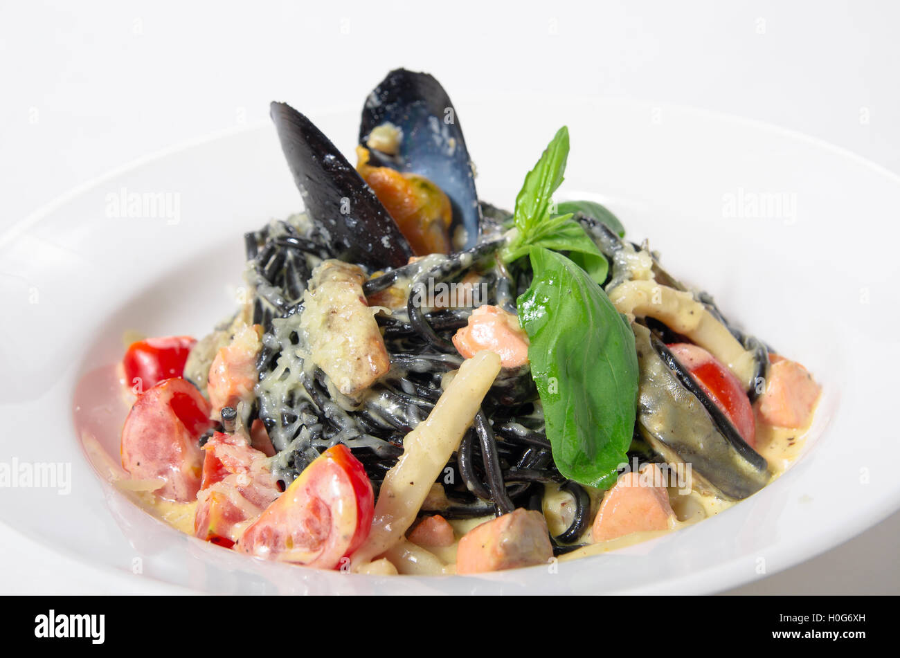 Spaghetti al nero di seppia, cozze, gamberi, calamari in una salsa cremosa con parmigiano Foto Stock