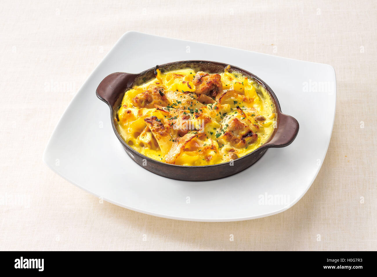 Il pollo e la pancetta salsa alla panna al gratin su piastra bianca sullo sfondo Foto Stock