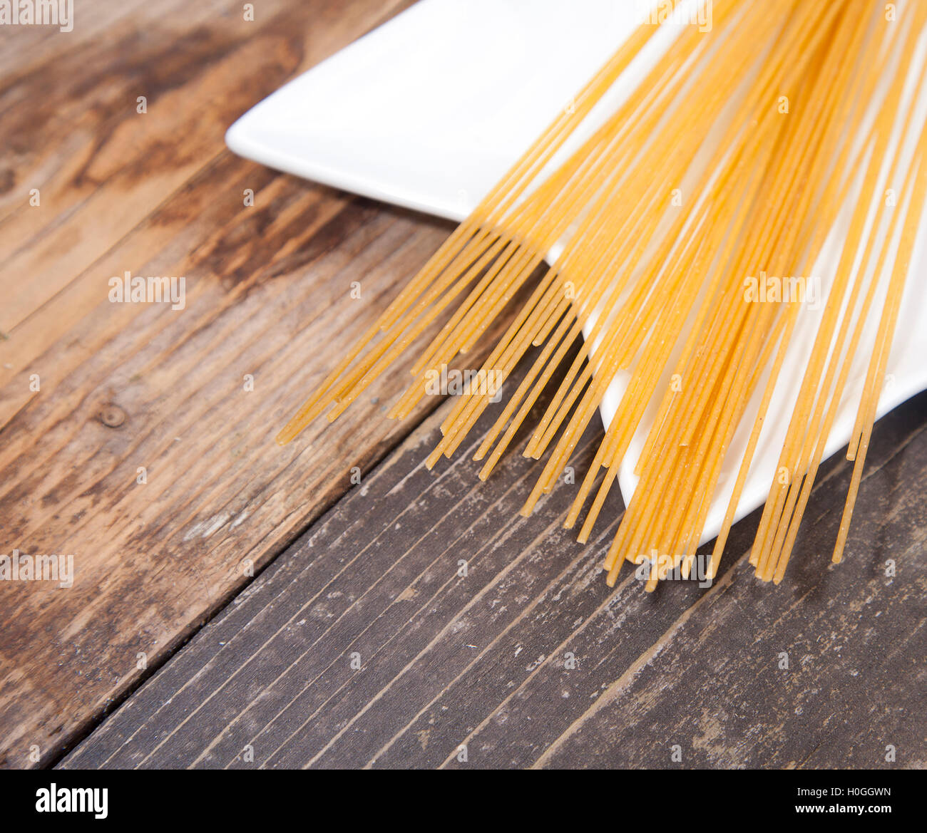 Pila di farro spaghetti sul piano bianco sul tavolo di legno Foto Stock