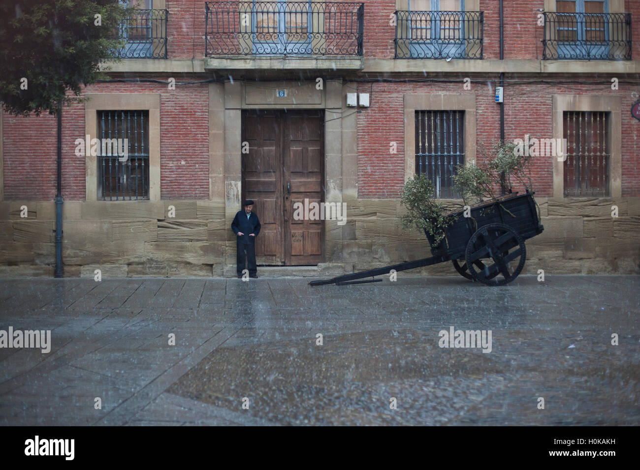 Un vecchio uomo ripara dalla pioggia in un villaggio plaza Camino de Santiago, route Francesca Foto Stock