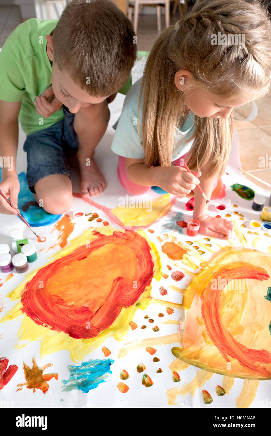 Fratello e Sorella di pittura insieme su un grande foglio di carta Foto Stock