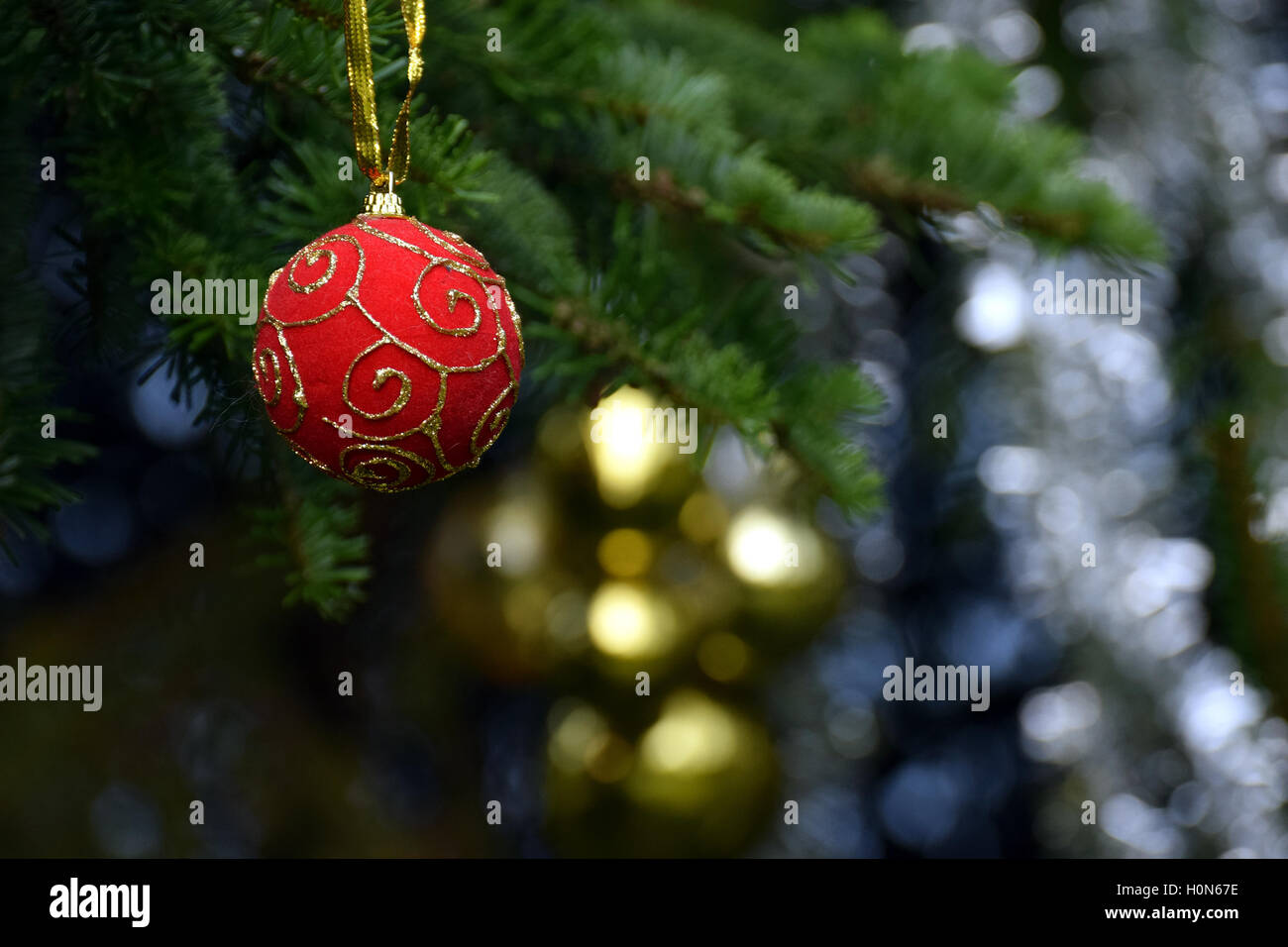 Decorazione di natale. Red palla di Natale appeso a un albero di natale. Palline dorate e tinsel sfondo. Foto Stock