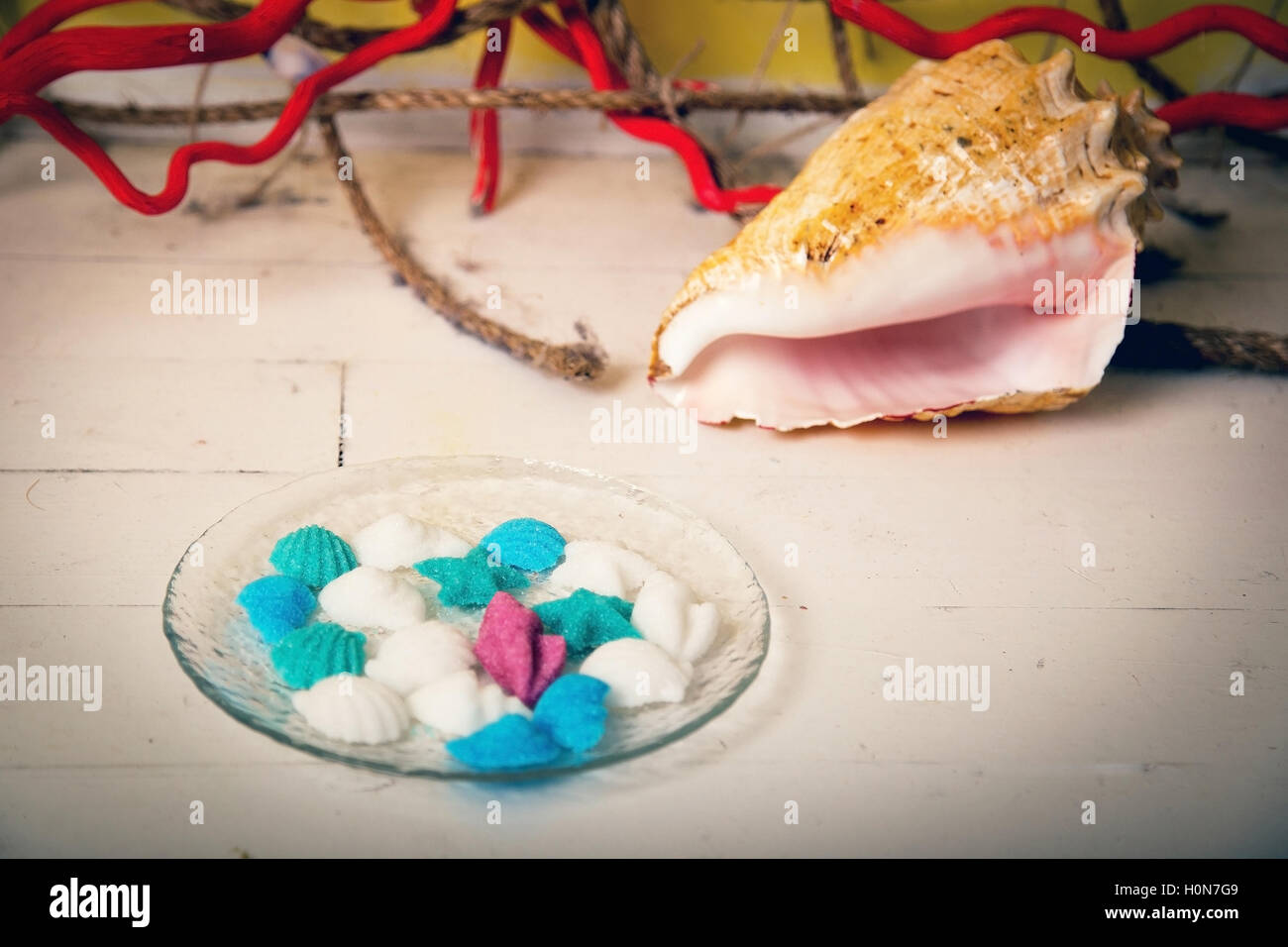 Figurine fatte di zucchero in un piatto di vetro con una grande conchiglia Foto Stock