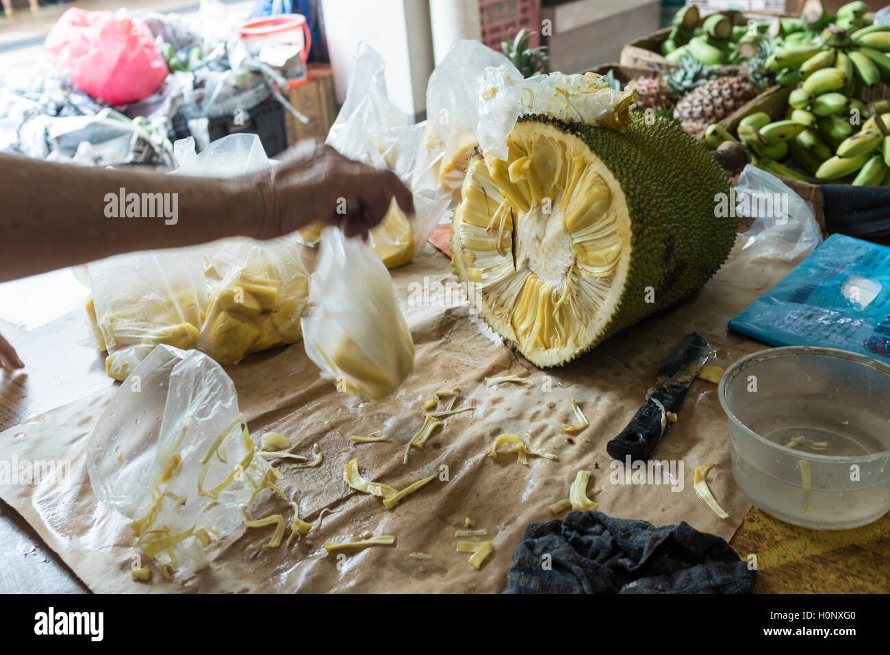 Un venditore di frutta taglia un martinetto frutto per la vendita in una fase di stallo nell'alloggiamento estate in Geylang Bahru in Singapore Foto Stock