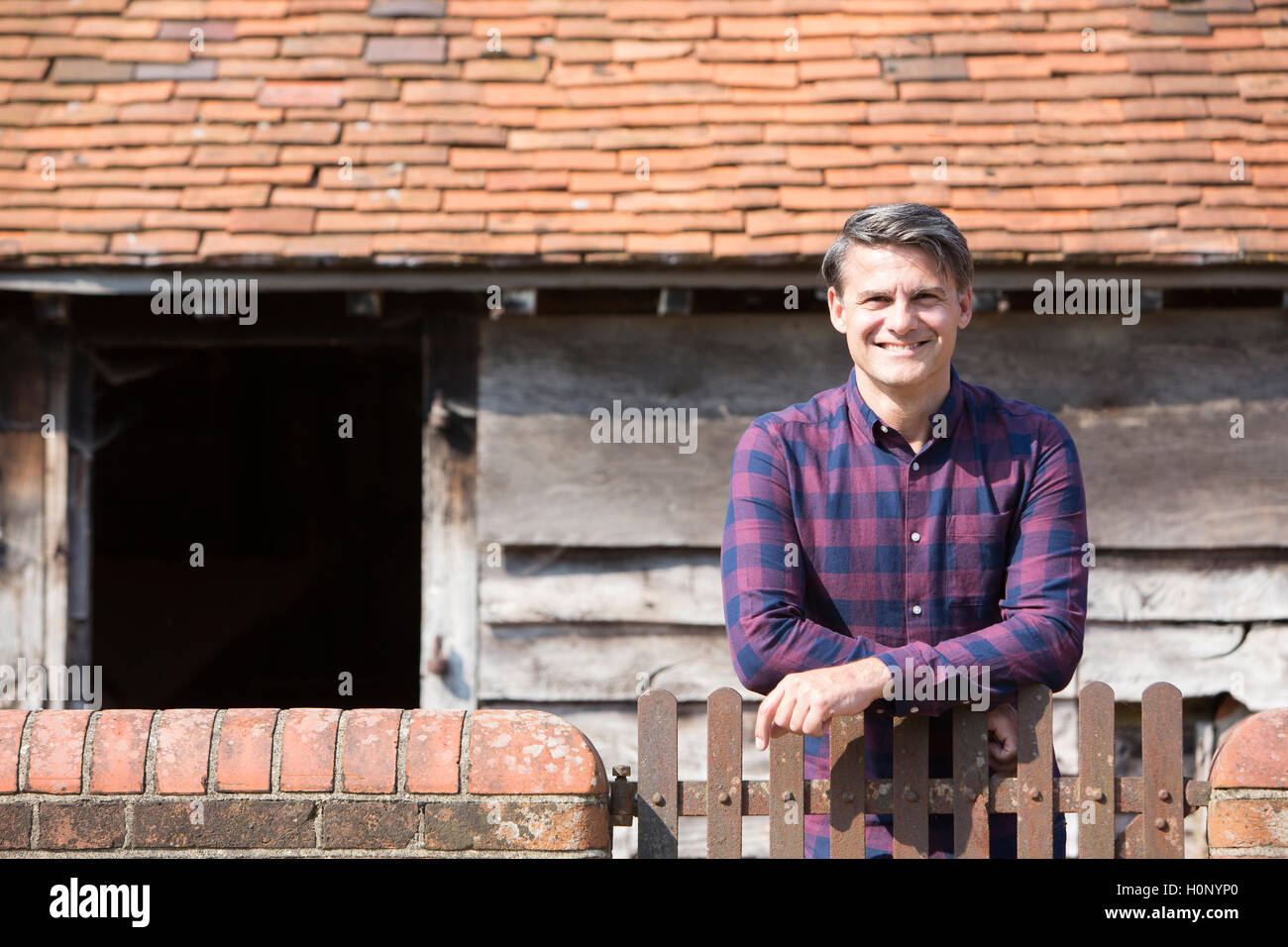 Ritratto di agricoltore guardando oltre il muro della Fattoria Foto Stock