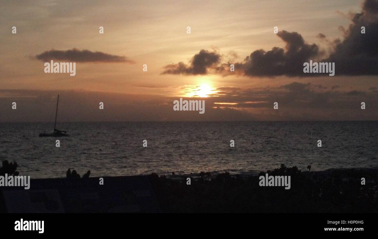 Aruba, Beach Sunset con barca a vela nel terreno centrale. Tramonto arancione con nuvole sullo sfondo, Ambiente tranquillo serale Foto Stock