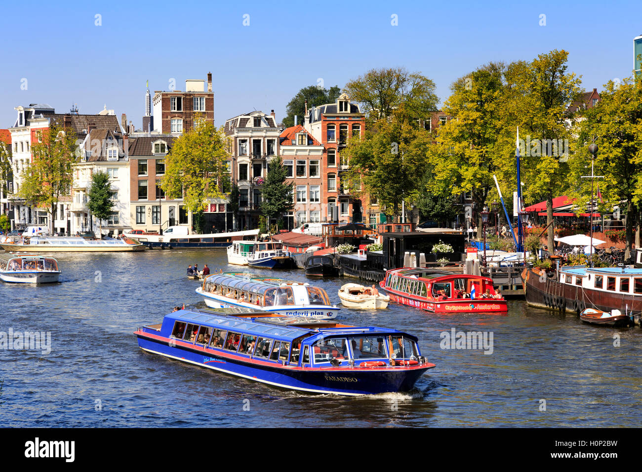 Le imbarcazioni turistiche sul fiume Amstel nel cuore di Amsterdam Foto Stock