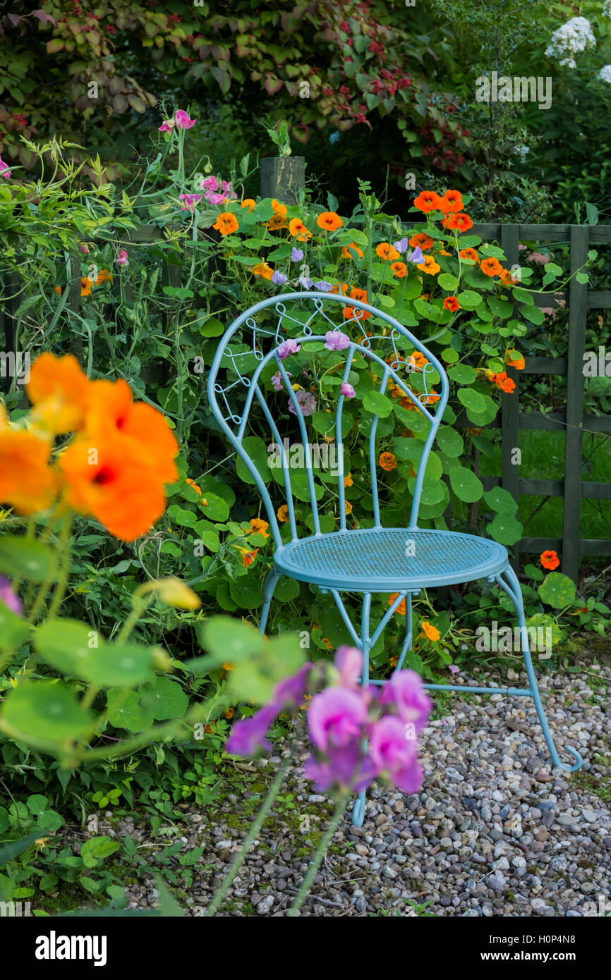 Elegante posto blu circondato da fiori in un giardino cottage. Foto Stock