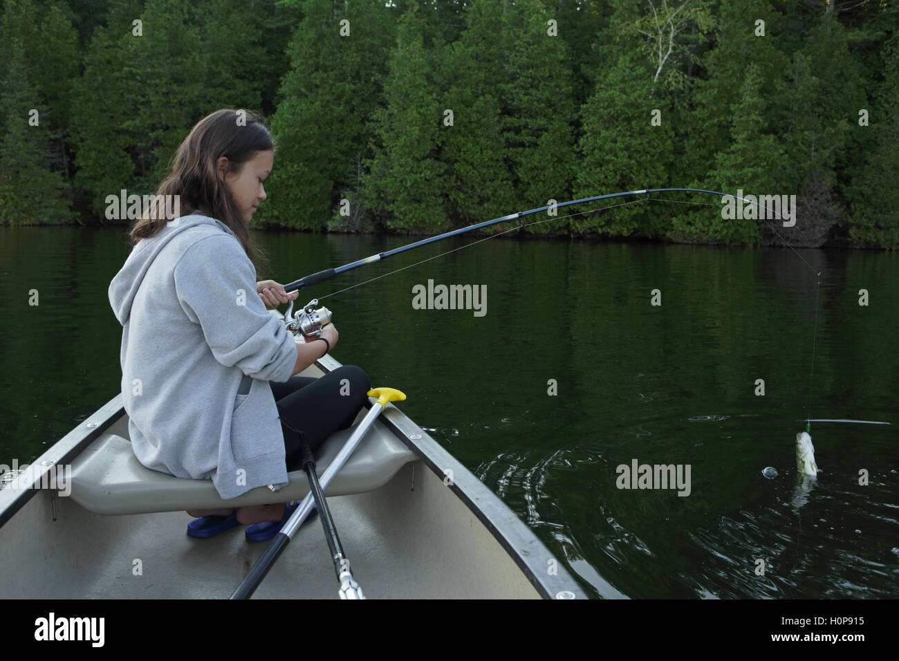 Ragazza la pesca la cattura di un bass da una canoa su un lago nel Vermont Foto Stock