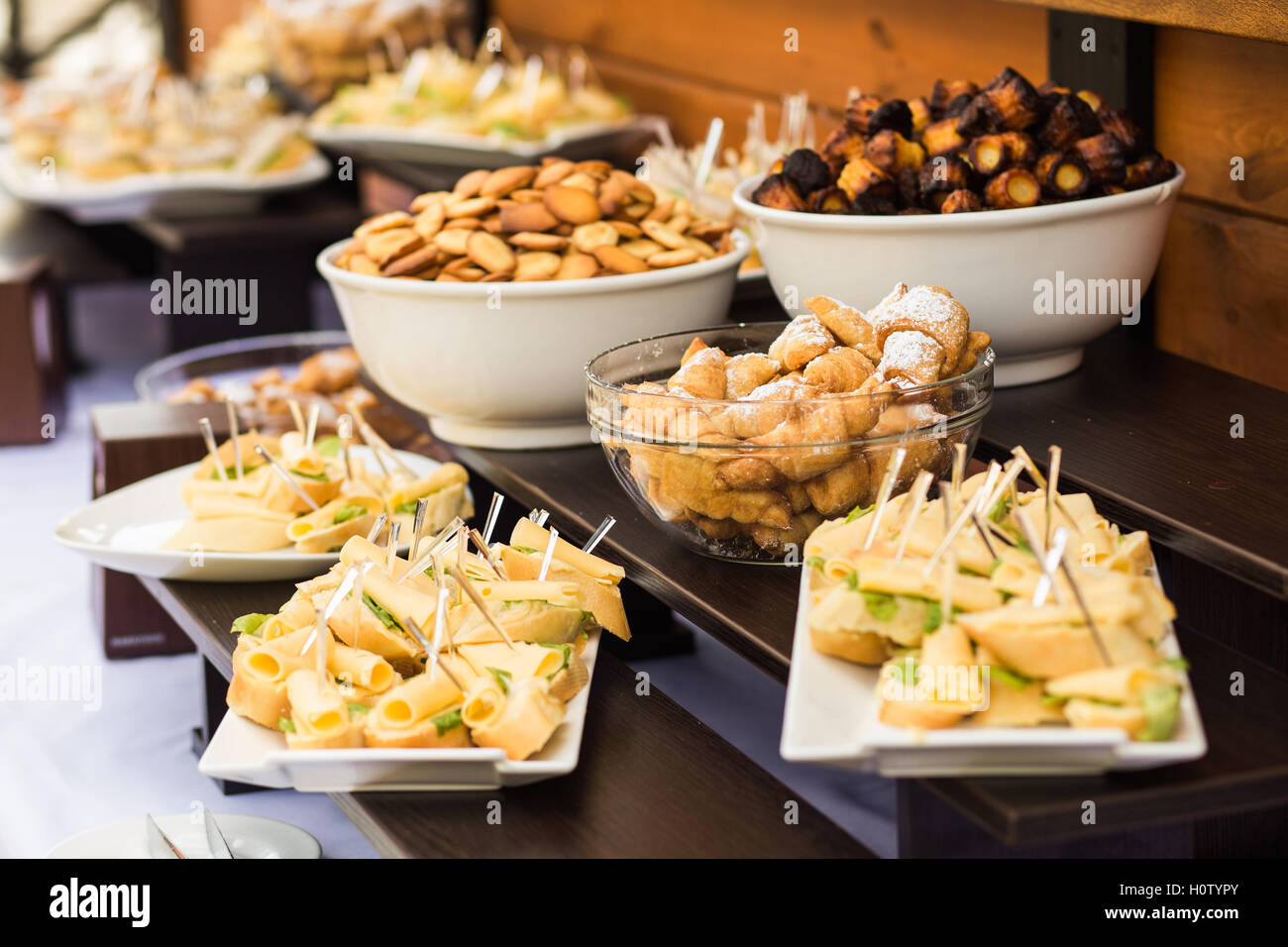 Il legno marrone Tavoli pieni di diversi spuntini per party o conferenze di affari. Le piastre bianche con formaggio panini e varietà di Foto Stock