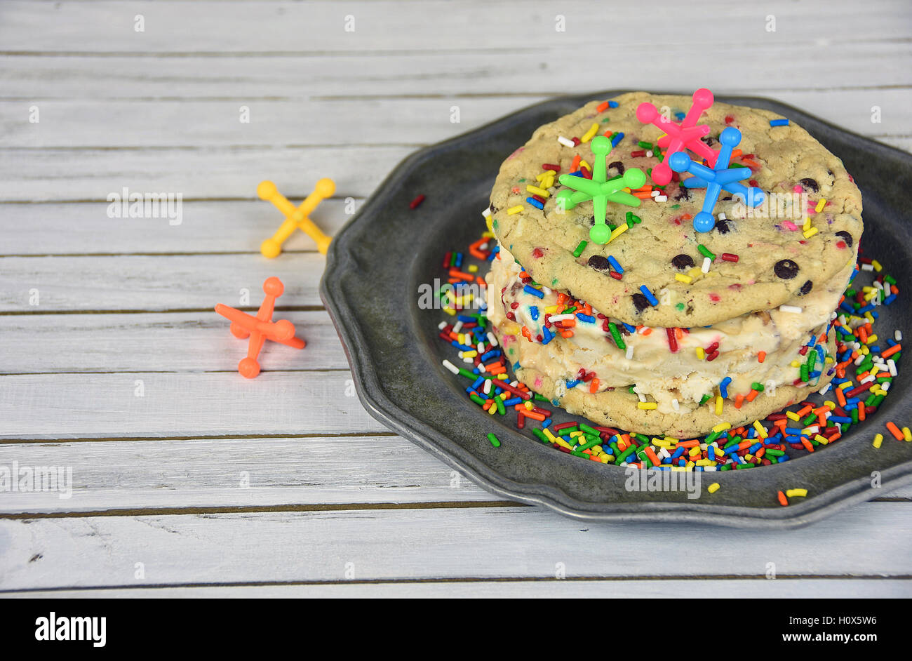 Martinetti giocattolo sul gelato a sandwich del cookie con rainbow spruzza sulla piastra in peltro Foto Stock