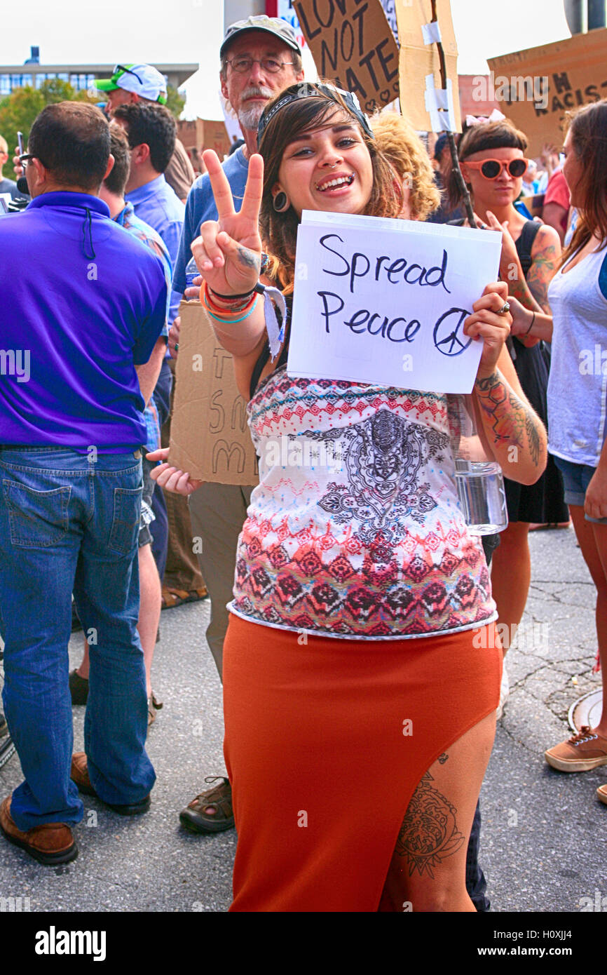 Giovane donna in possesso di un banner di pace a un meeting vincente in Asheville NC Foto Stock