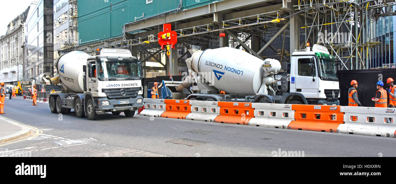 Pronto misti calcestruzzo di cemento carrello City of London street parzialmente segregato per sito in costruzione camion di consegna il caricamento nella tramoggia di gru England Regno Unito Foto Stock