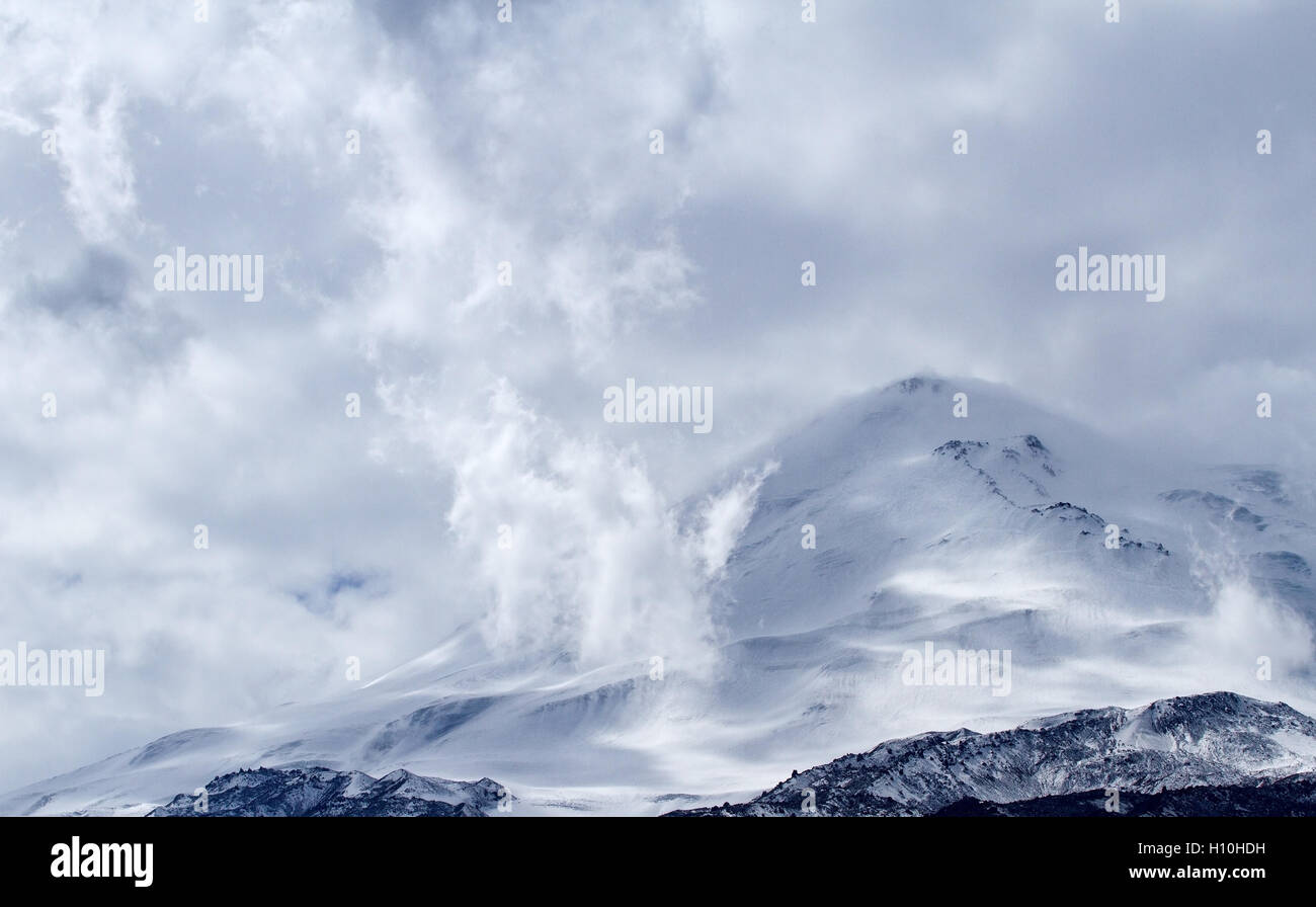 Elbrus mountain (uno dei la più alta montagna della regione del Caucaso) coperto di neve con le nuvole sopra di esso. Foto Stock