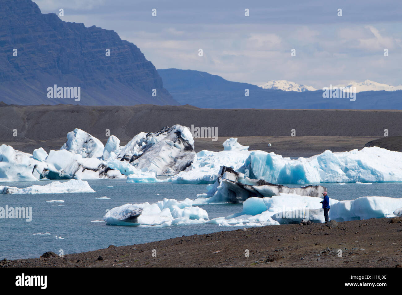 Turistico con fotocamera sulla morena glaciale jokulsarlon laguna glaciale con gli iceberg sud dell'Islanda Foto Stock