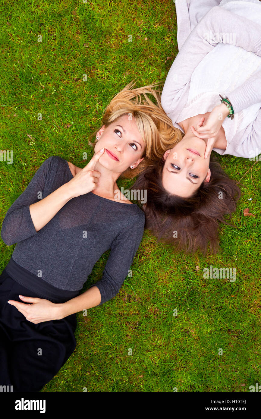 Due ragazze pensosa giacente in erba Foto Stock