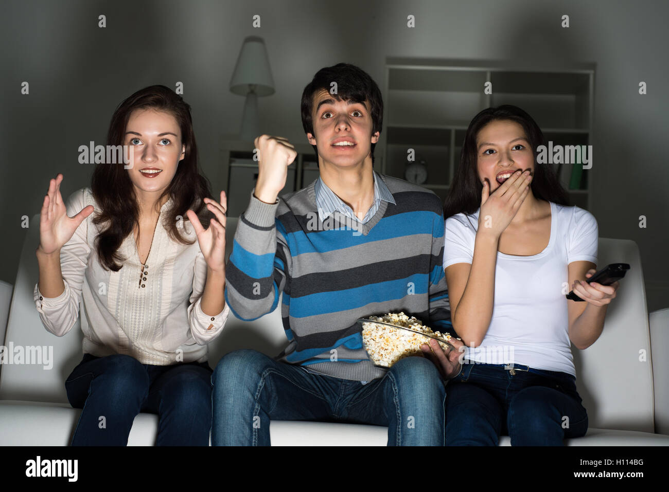 Un gruppo di giovani di guardare la TV sul lettino Foto Stock