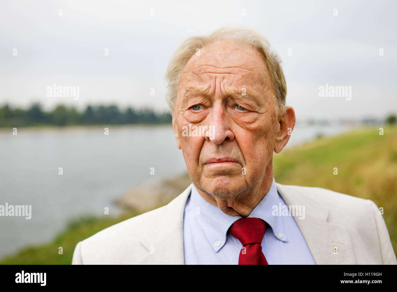 Senior uomo 80 in posa di fronte fiume, vicino up shot in estate, sguardo premuroso Foto Stock